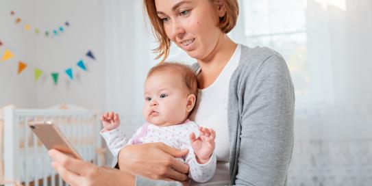 Mutter mit Baby schaut aufs Handy