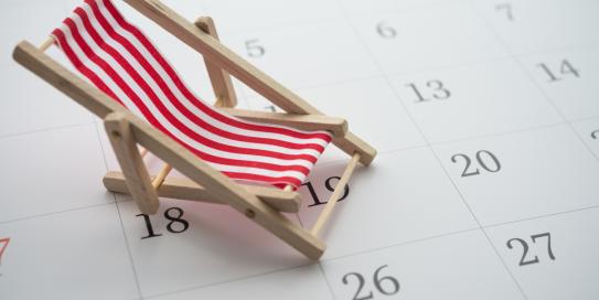 Klappstuhl auf einem Kalender - Symbol für Sommerurlaub